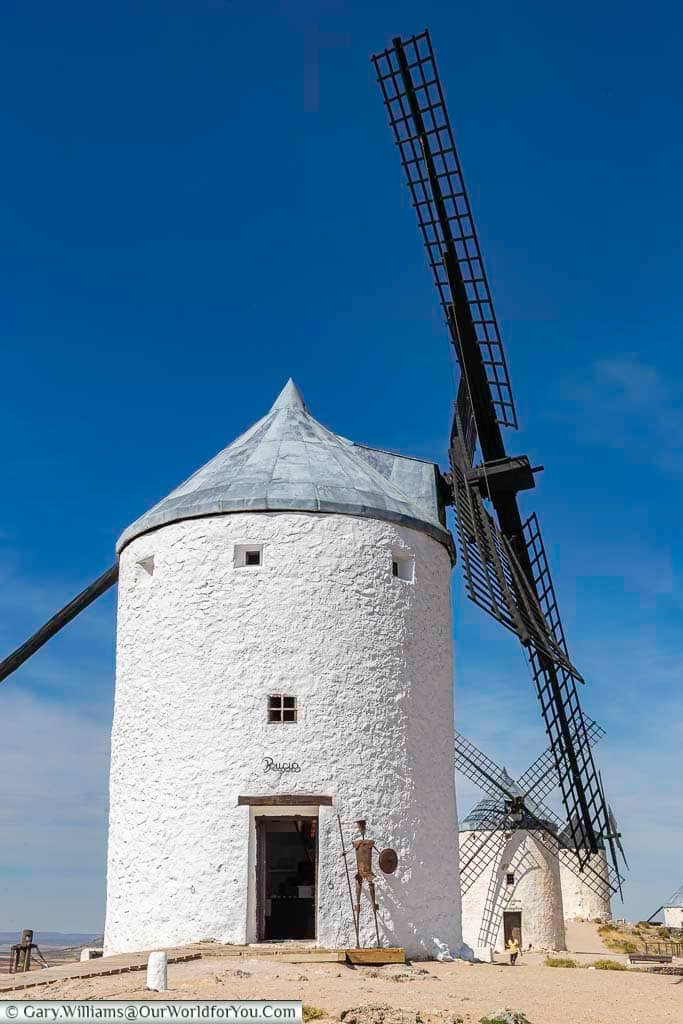 An ancient white windmill in consuegra named ruscio, with three other windmills in the distance