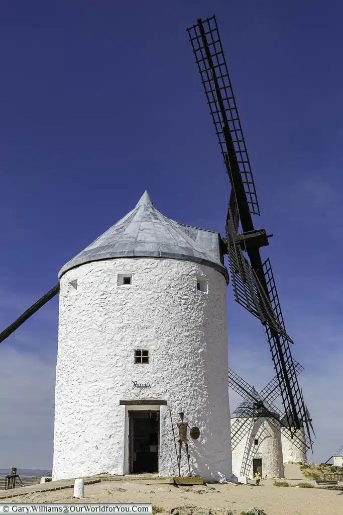 An ancient white windmill in consuegra named ruscio, with three other windmills in the distance