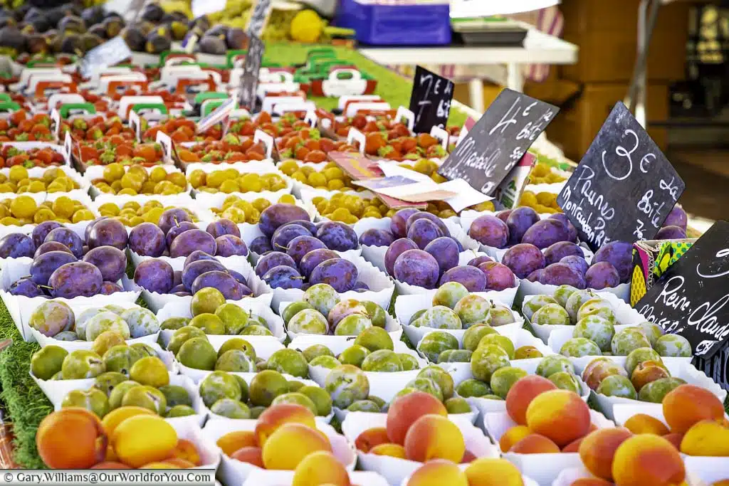 A fine selection of fresh softs fruit on market stall in Nice, France. The stall is beautifully laid out with the bright colours of peaches, greengages, plums, kumquats and strawberries