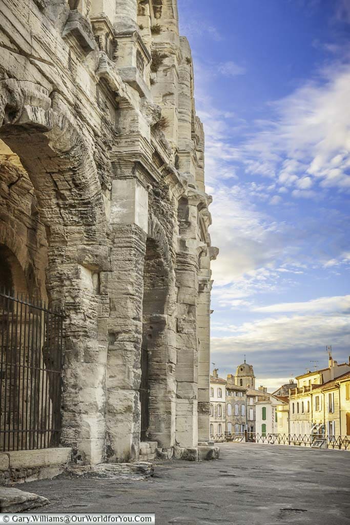 A view of the french town of arles in provence featuring the edge of the historic roman amphitheatre with a view towards the centre of town bathed in golden light