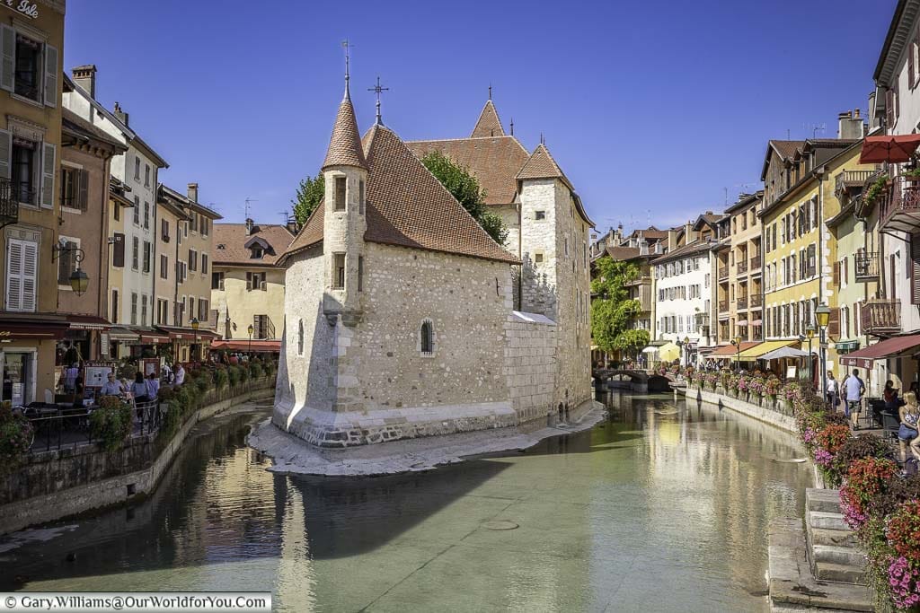 the fortified stone palais de l'Île in the centre of the le thiou river in the heart of the historic alpine town of annecy on a bright clear day under blue skies