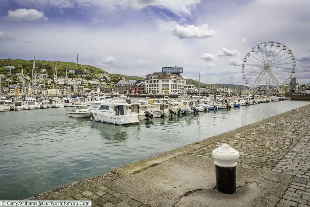 A series of small boats in the marina, with the ferris wheel in the background at fécamp, in the normandy region of france