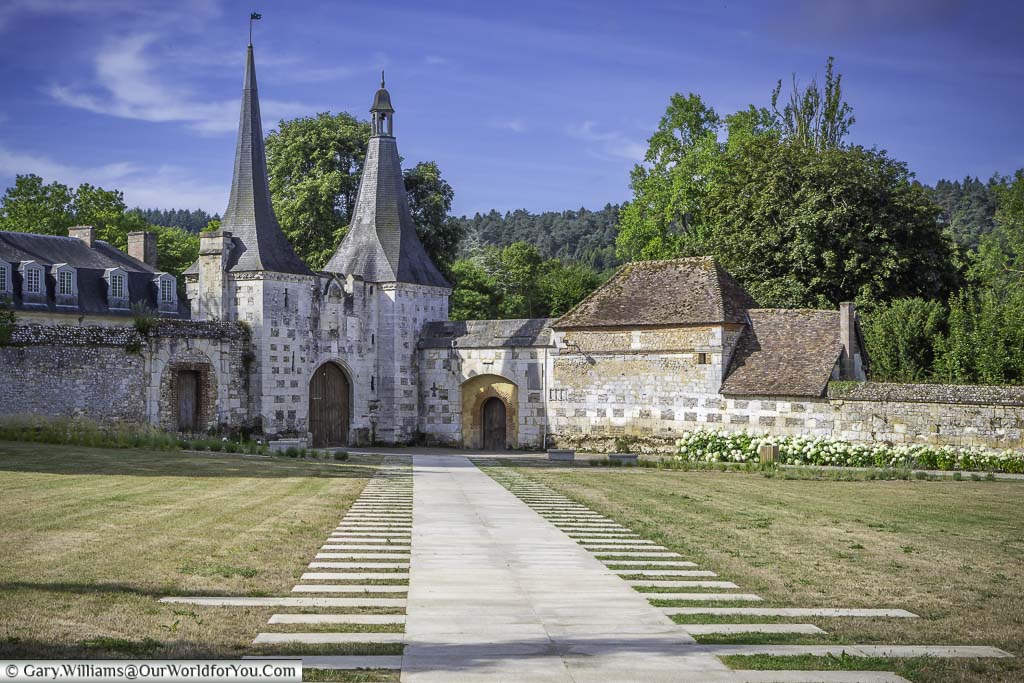 A pathway to the twin-towered gateway of the abbaye du bec-hellouin in the normandy, france