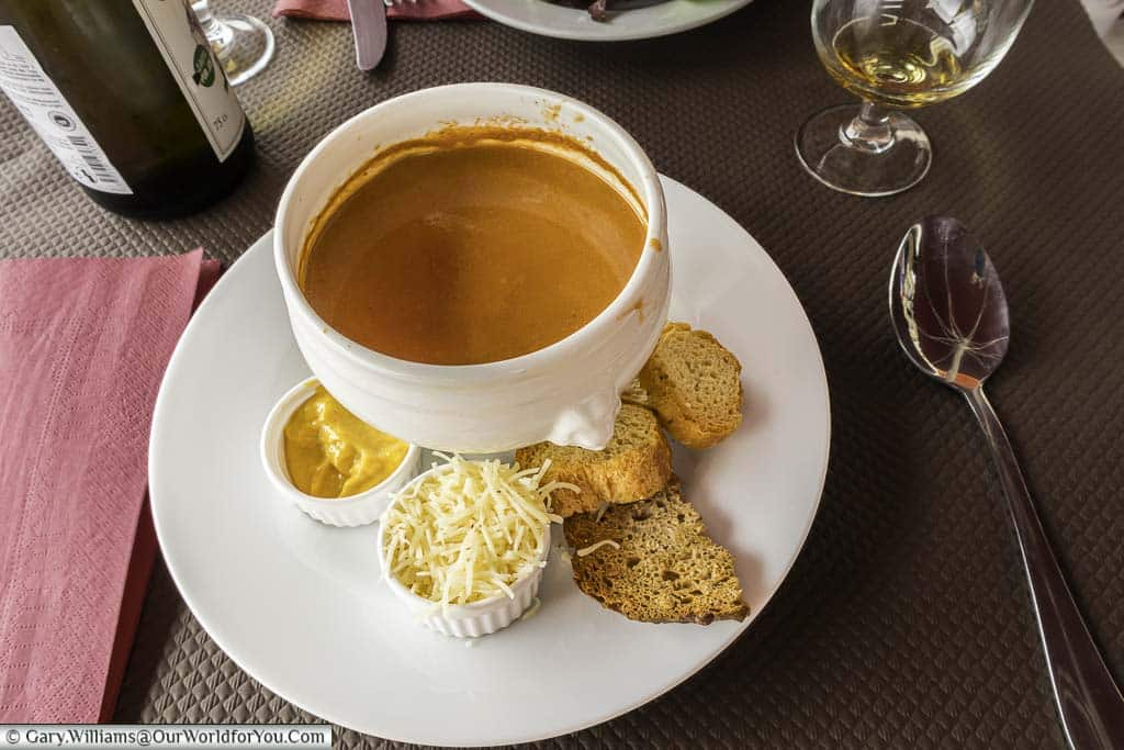 Traditional bowl of fish soup served with crispy croutons, grated hard cheese and a remoulade on the side