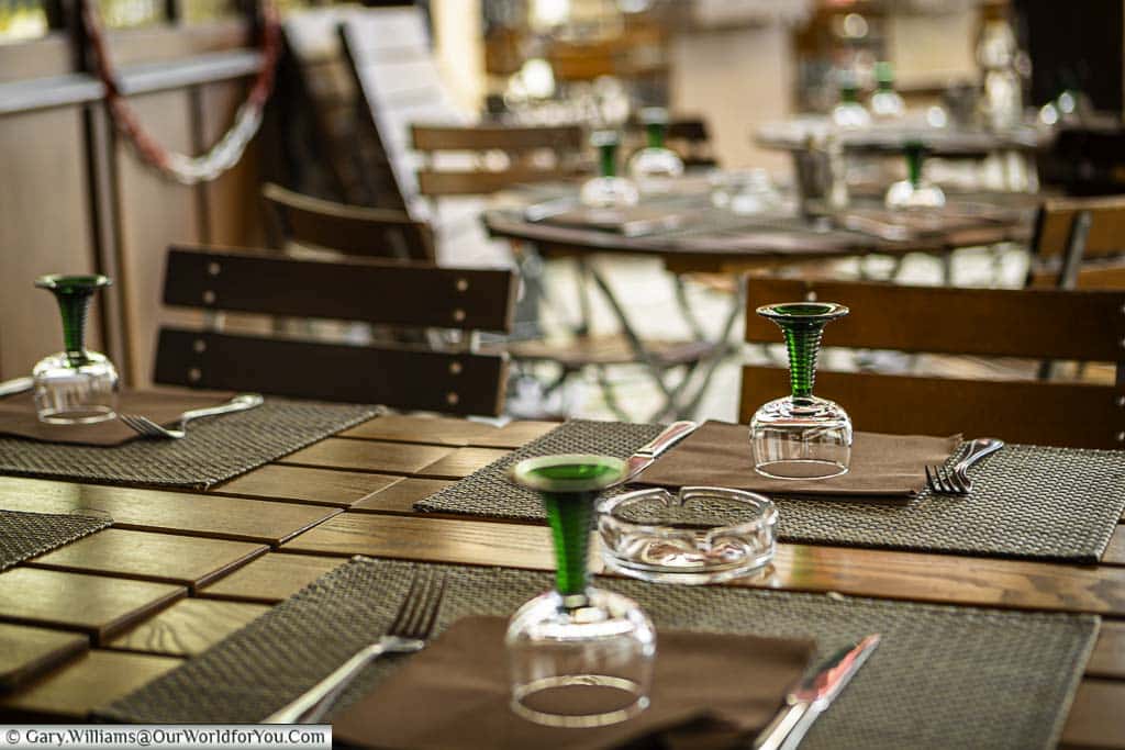 Tables and chairs at a cafe in the Alsace region of France with the distinctive green glass stemmed wine glasses synonymous with the area.