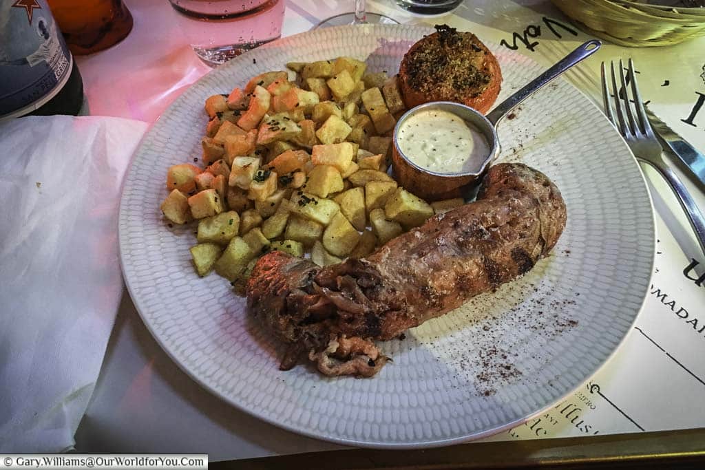 an andouillette de troyes sausage served with sauteed potatoes, a roasted tomato and a creamy sauce
