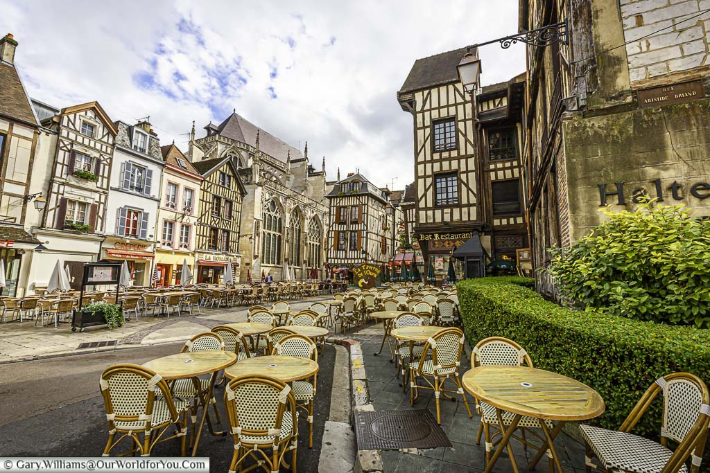 A view of a mass of tables and chairs on the pavement side of the historic city of Troyes. The backdrop is the half-timbered buildings synonymous with the region.