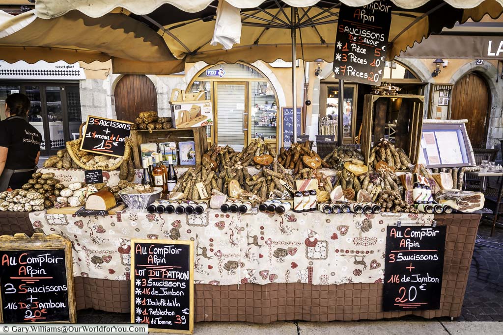 Stall in Annecy’s food market displaying regional cured hams, meats and sausages.