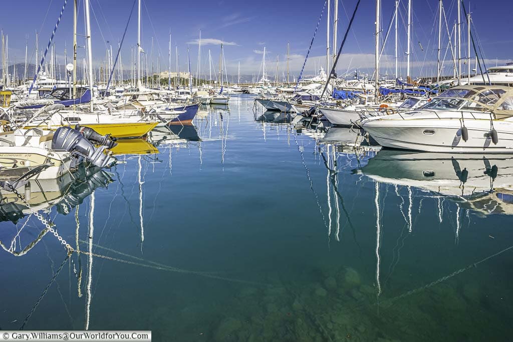 sailing boats moored in the clear waters of the marina at antibes on the cote d'azur in the south of france.