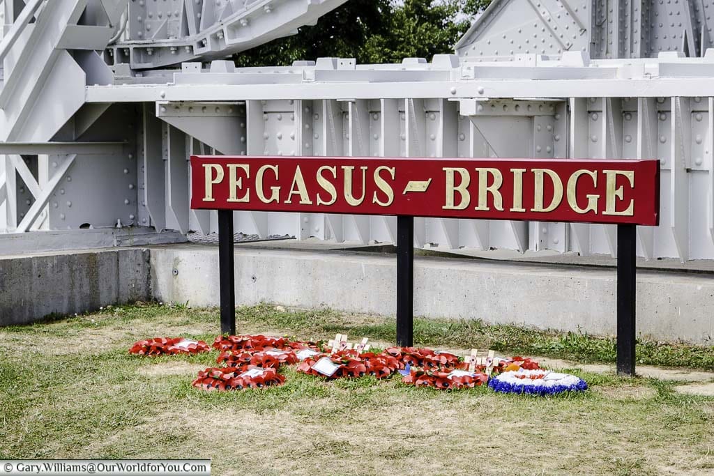 Remembrance wreaths placed under the sign for the Pegasus Bridge in Normandy.