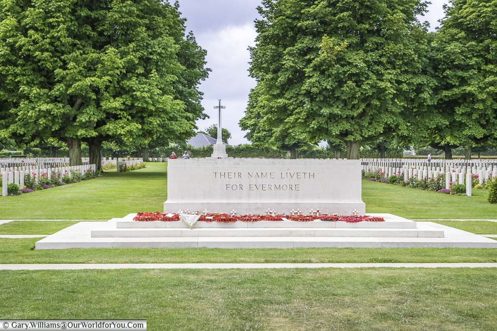 The 'Stone of Remembrance', with the 'Cross of Sacrifice' in the background, flanked on each side by headstones, at the Bayeux Commonwealth Military Cemetery in Normandy.