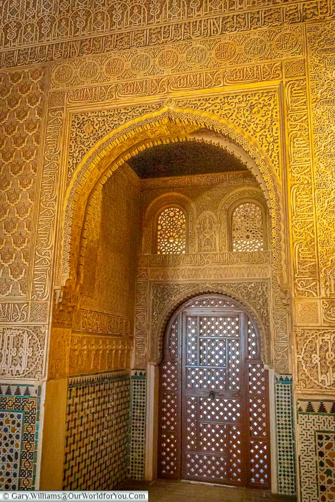An intricate archway decorated with moorish inscriptions inside the alhambra palace in granada spain