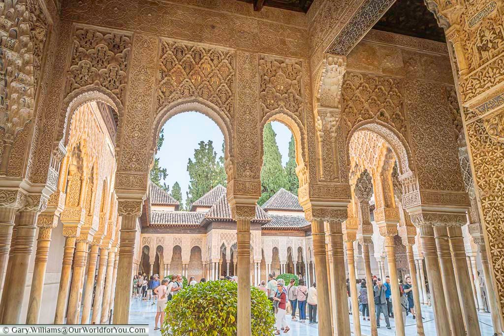 A series of intricate archways decorated with moorish inscriptions leading to from the palace of the lions in the alhambra palace in granada spain