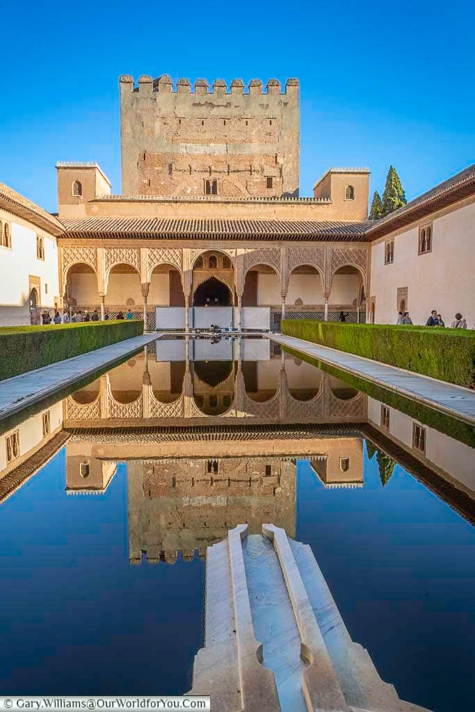 The tower at the end of the court of the myrtles reflected in the pond that runs the entire length of the alhambra palace in granada spain