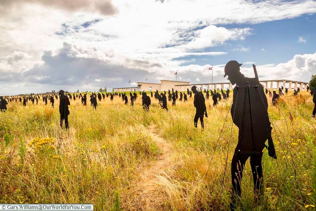 A sea of silhouetted figures of the standing with giants installation in front of the british normandy memorial in france