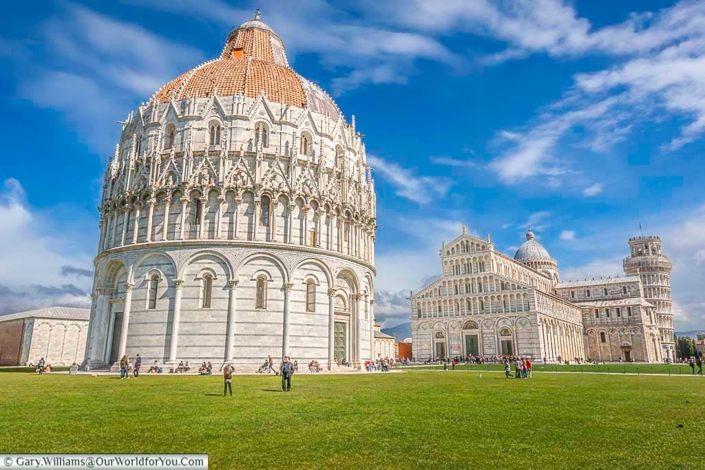 The domed battistero di san giovanni in front of the cathedral of pisa with the iconic learning tower of pisa in the background