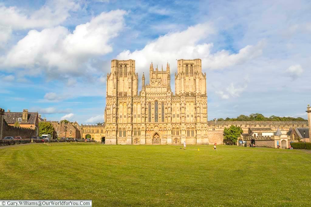 A view across wells green capturing the ornate west-facing side of wells cathedrals in the golden light of early evening