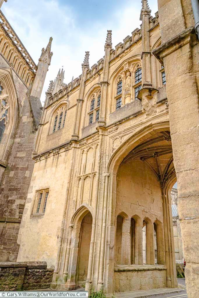 The gothic chain gate with a walkway over the top crossing cathedral green in wells, somerset