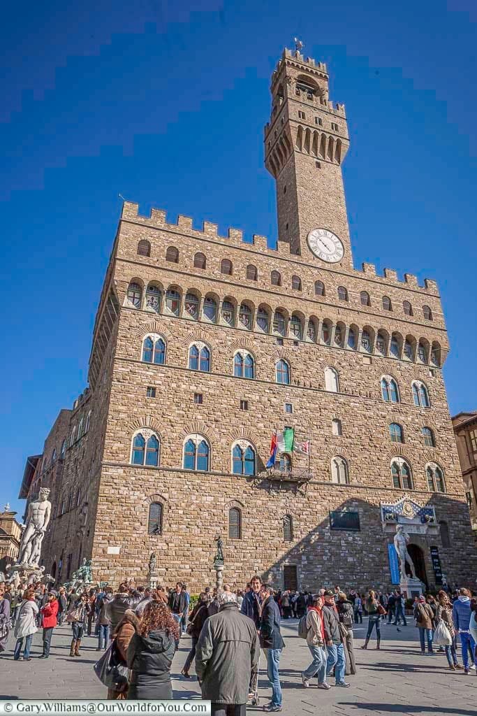 The fortified palazzo vecchio with its giant clock tower in the piazza della signoria, florence, italy