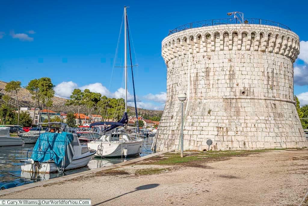 The 10-metre tall, circular stone saint marks tower, with boats moored alongside it in trogir, croatia