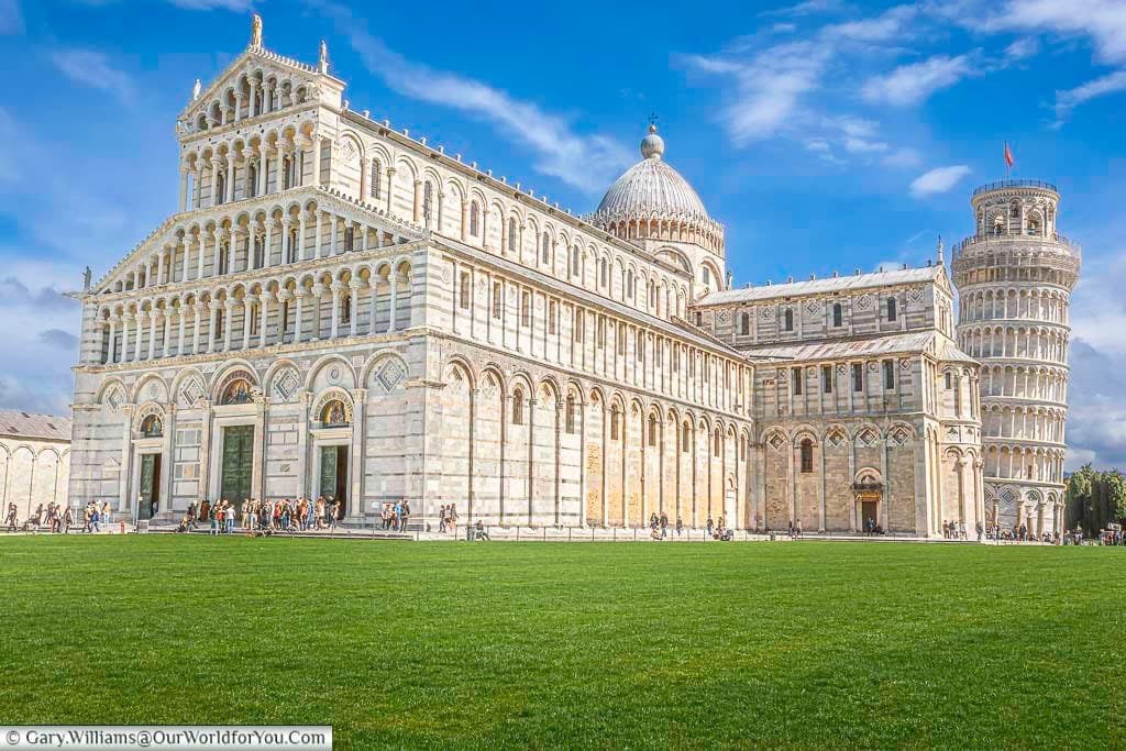 The cathedral of pisa with the iconic learning tower of pisa to it's right on a bright day in tuscany, italy