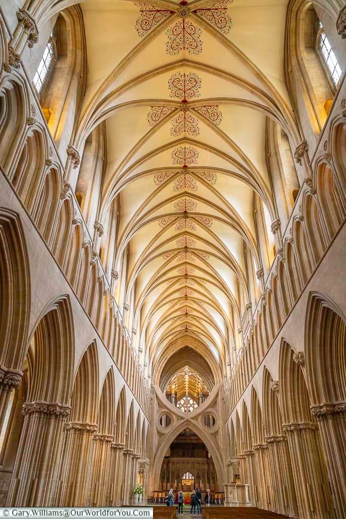 The view along the central isle of wells cathedrals with its ornate ceiling and strong stone columns to the scissor arch in front of the altar