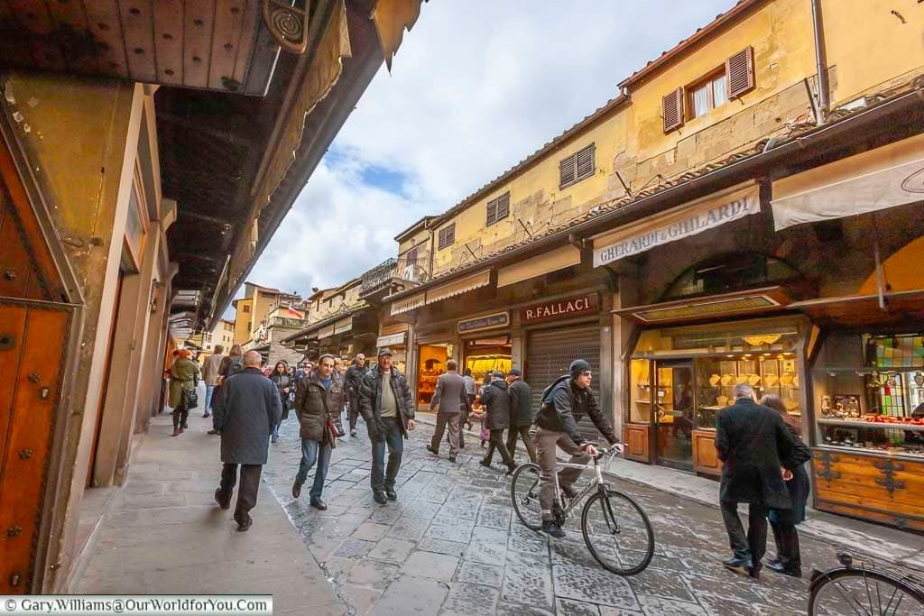 a street scene of people passing the shops on the ponte vecchio in florence, italy