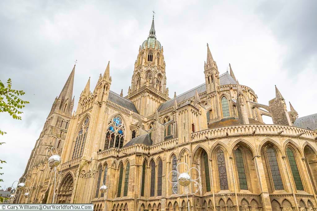 The historic 13th-century Gothic cathedral of Bayeux on a grey day in July with glitterball daisies in the foreground