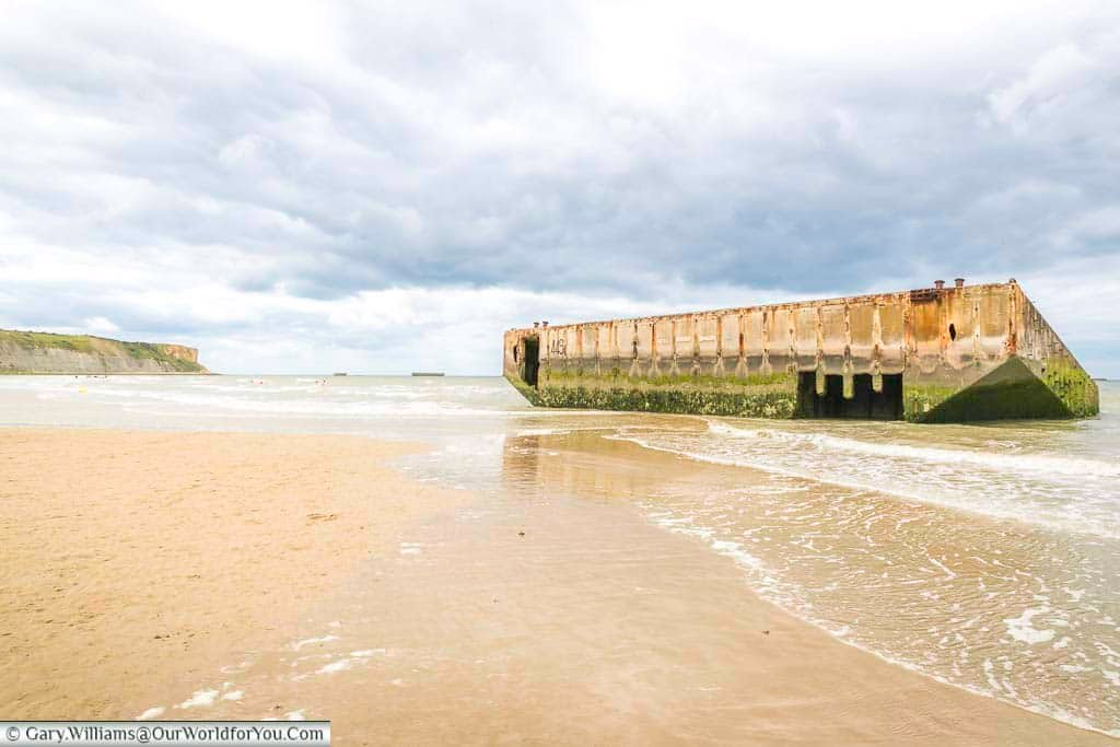 Waves lapping around a piece of the mulberry harbour from the d-day landings in normandy that has washed ashore in arromanches-les-bains, france