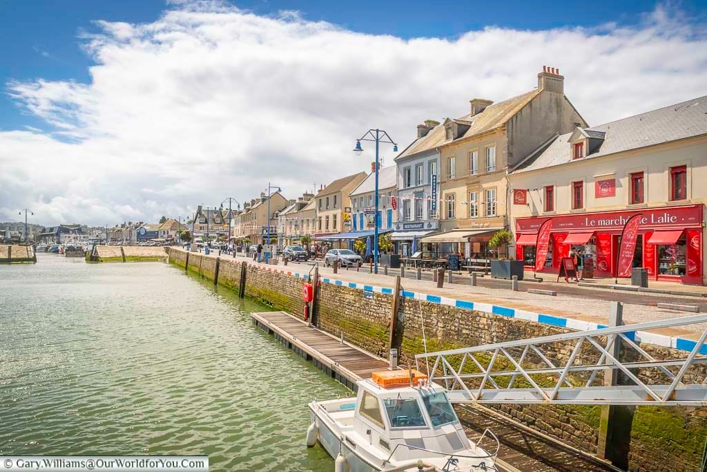 The view of the harbourside of port-en-bessin in normandy, france, lined with restaurants and shops, on a bright day in july