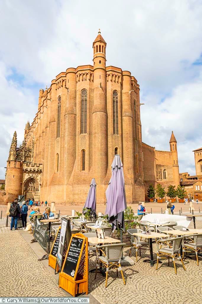 A cafe in front of the giant red brick albi cathedral in the occitania region of southern france