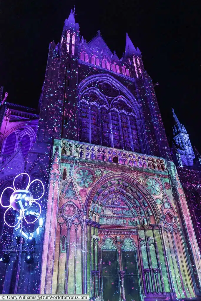 The light show projected onto the southern entrance to Bayeux Cathedral at night in a blue and pink