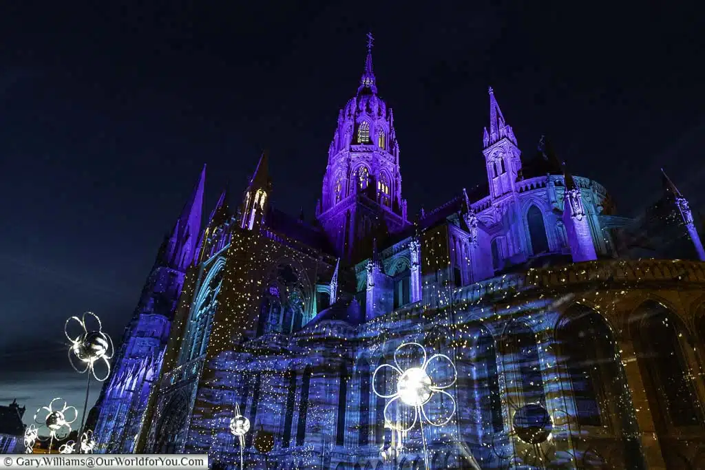 The light show projected on Bayeux Cathedral at night giving it a blue hue and sprinkled in white lights reflected from the glitterball daisies