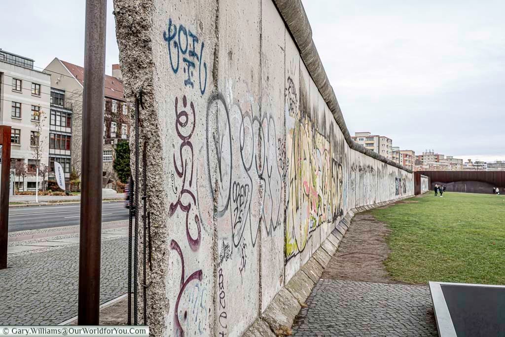 A view of a split in the Berlin Wall allowing you to see both the east & west sides.