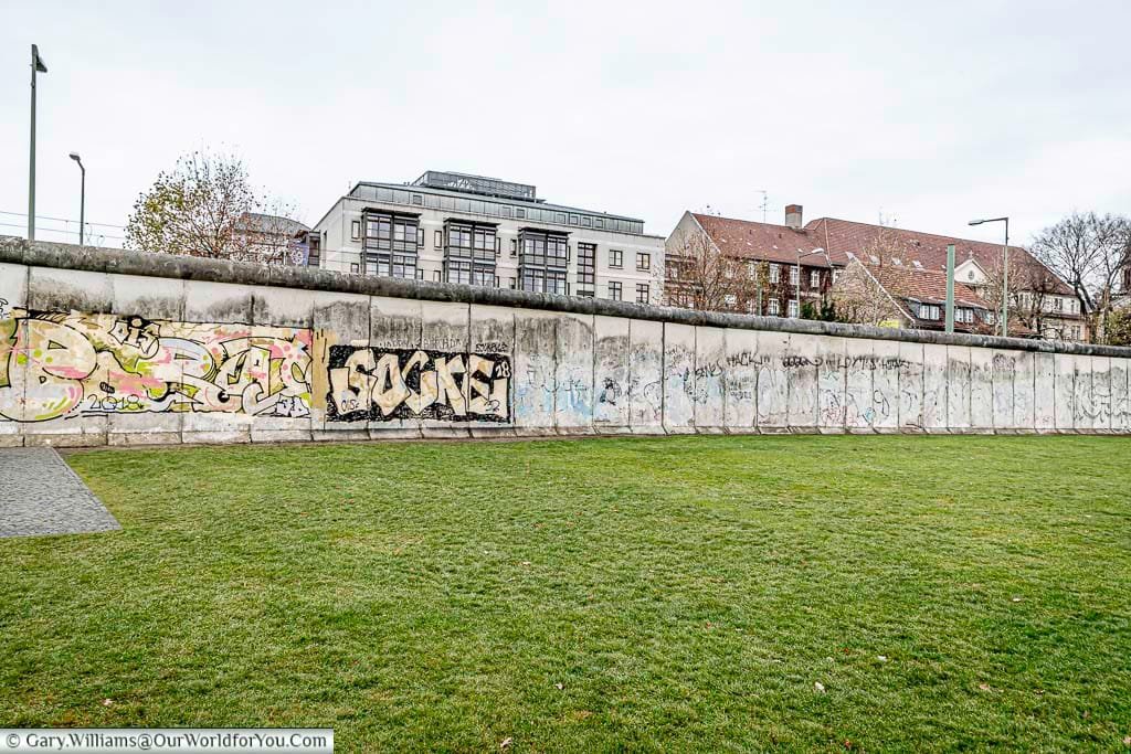 A grey and bleak view of the Berlin Wall from the grass area that's was once known as the "Death Strip"