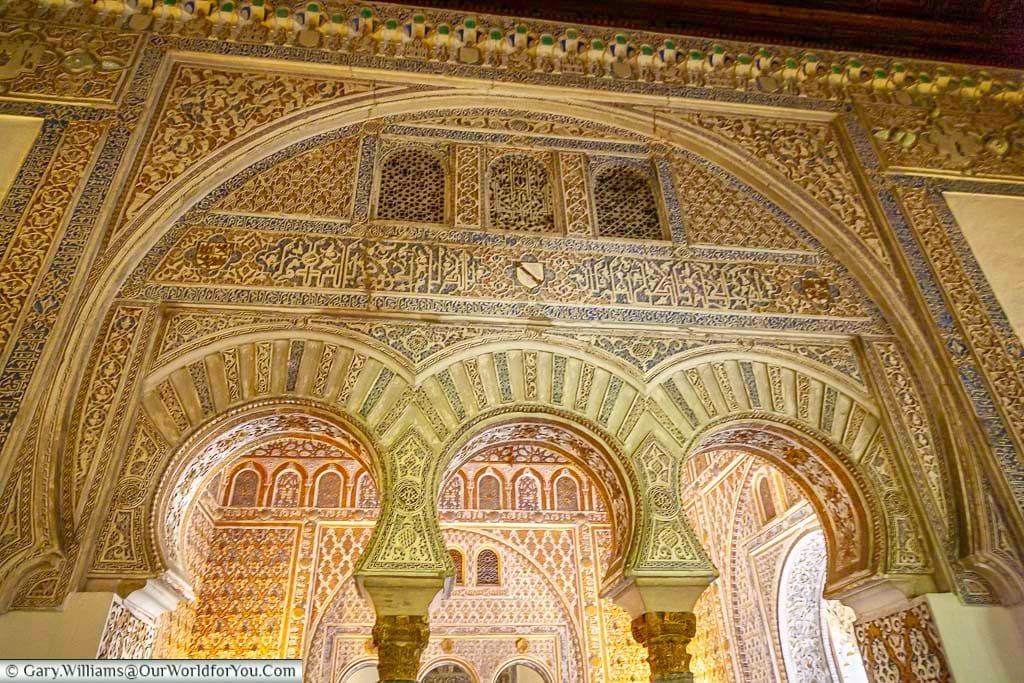 A closeup look through one ornately decorated Moorish arch, to a room as equally ornate inside Seville's Alcazar.