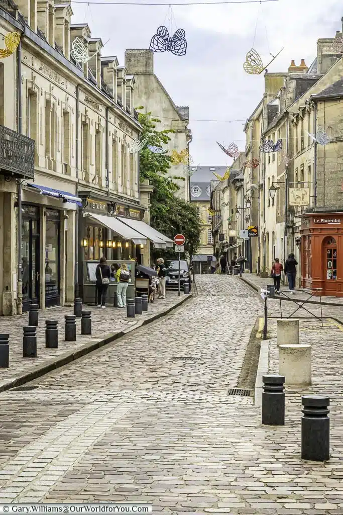 a quiet cobbled street with a pavement bistro on the side in bayeux, normandy, france