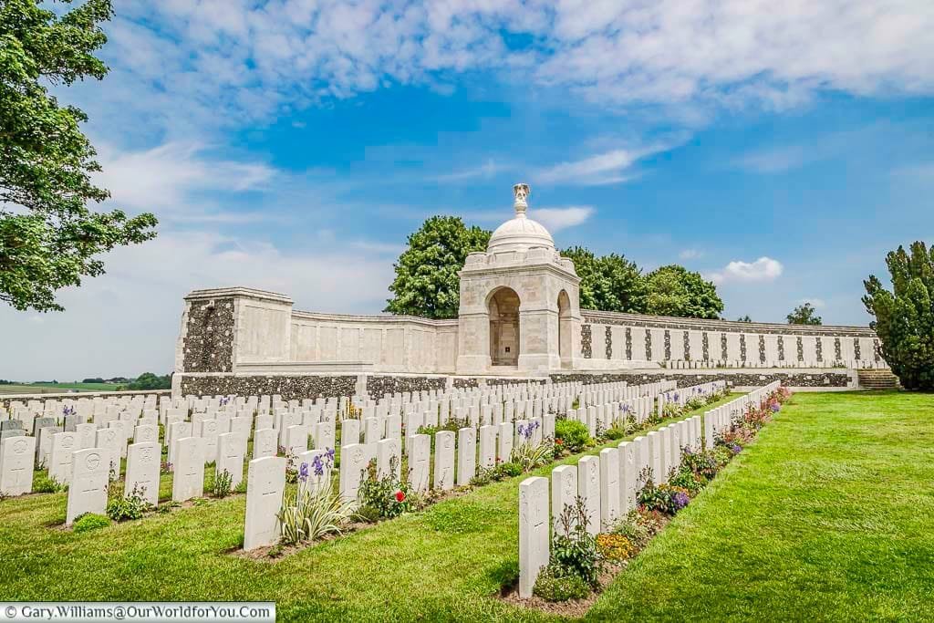 A view over rows of headstones to the memorial wall of the Tyne Cot Memorial in Belgium