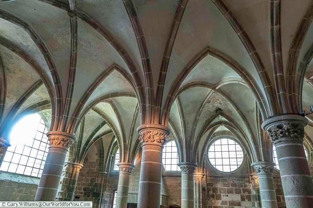The Knights Hall of Mont-Saint-Michel Abbey, with its numerous columns supporting a vaulted ceiling.