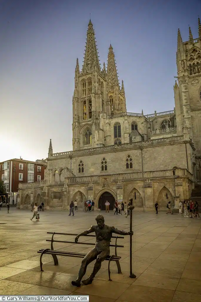 A monument to a pilgrim depicted as a brass figure sitting on a bench in burgos in front of the cathedral