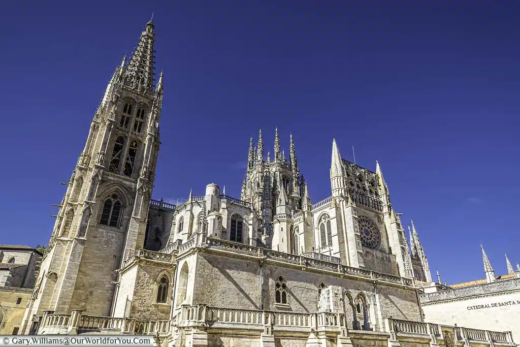 The southern face of the golden-coloured stone gothic burgos cathedral on a bright sunny day in northern spain