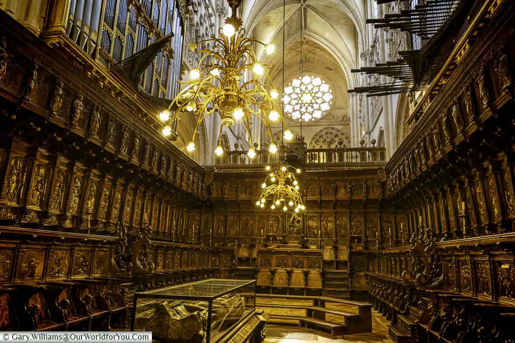 The dark wood panelled choir illuminated by brass chandeliers inside Burgos cathedral in northern Spain.