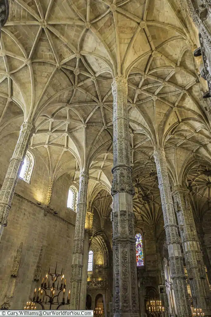Tall stone columns leading to the vaulted ceiling of the Mosteiro dos Jerónimos in the Belém region of Lisbon, Portugal