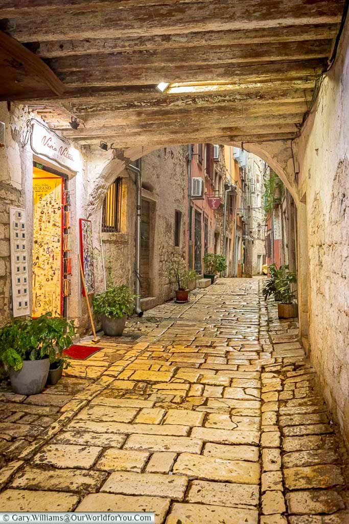 a covered archway over a quaint cobbled back street in rovinj, croatia