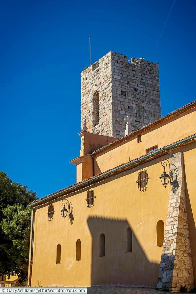 The Church of the Immaculate Conception in Antibes, France, stands out with its stone bell tower and vibrant yellow facade against a clear Mediterranean sky. This architectural gem reflects the region’s rich cultural heritage and offers a striking visual within the historic old town.