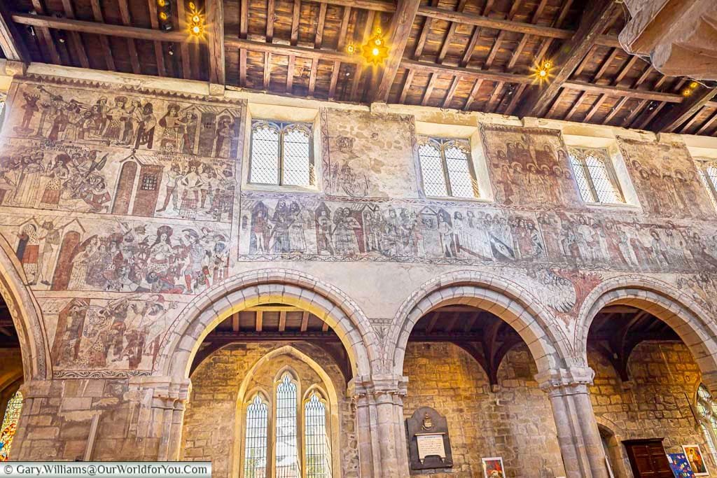 A detailed view of medieval wall paintings inside a historic Yorkshire church, showcasing intricate religious scenes beneath a timber-beamed ceiling and arched stone windows. These rare frescoes highlight Yorkshire’s rich cultural heritage, making it a fascinating stop for history lovers and travelers exploring England.