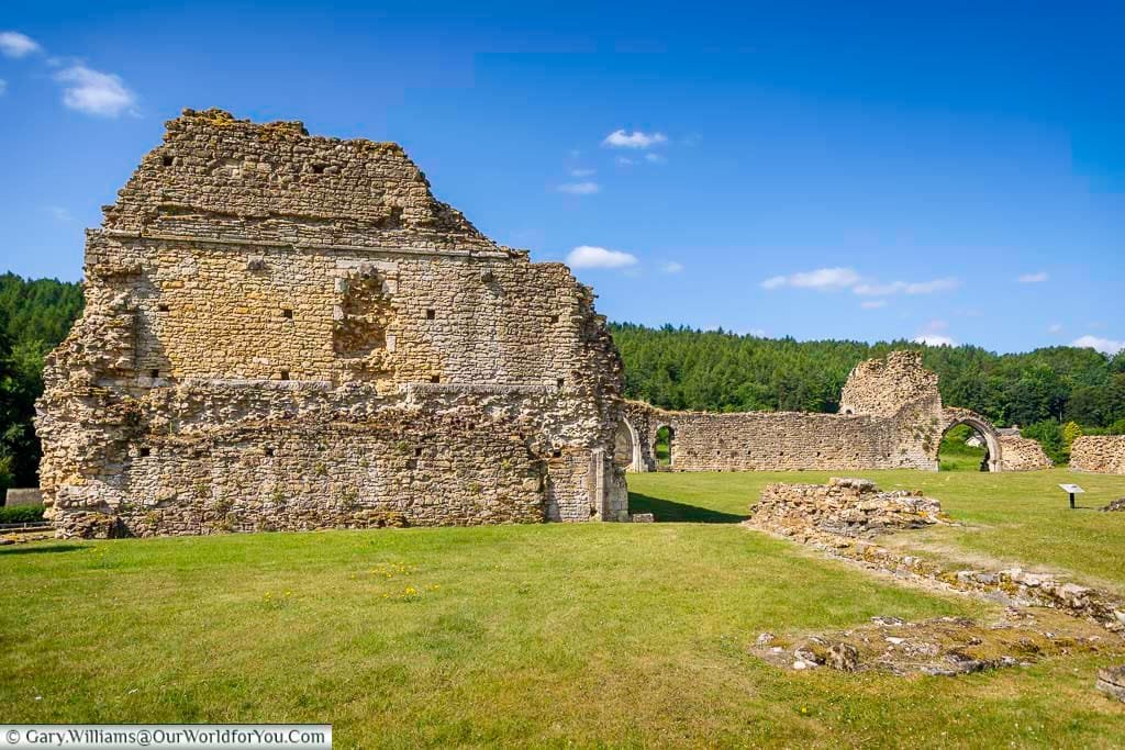 A stunning view of the ancient ruins of Kirkham Abbey in Yorkshire, England, set against a backdrop of lush green forest and blue skies. This peaceful heritage site offers a glimpse into medieval monastic life and is a must-see hidden gem for visitors exploring Yorkshire.