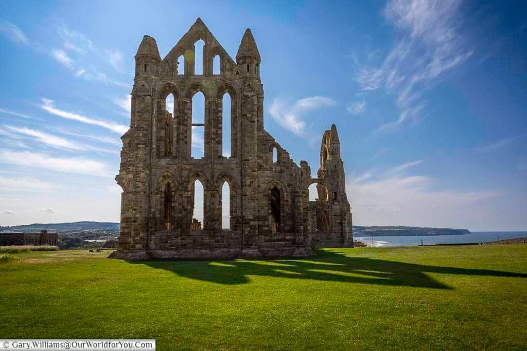 the dramatic silhouette of Whitby Abbey against a bright sky, a truly iconic and historic place in Yorkshire, England. This ancient ruin is a must-see stop on any English road trip, offering a glimpse into Whitby's rich past and stunning coastal views.