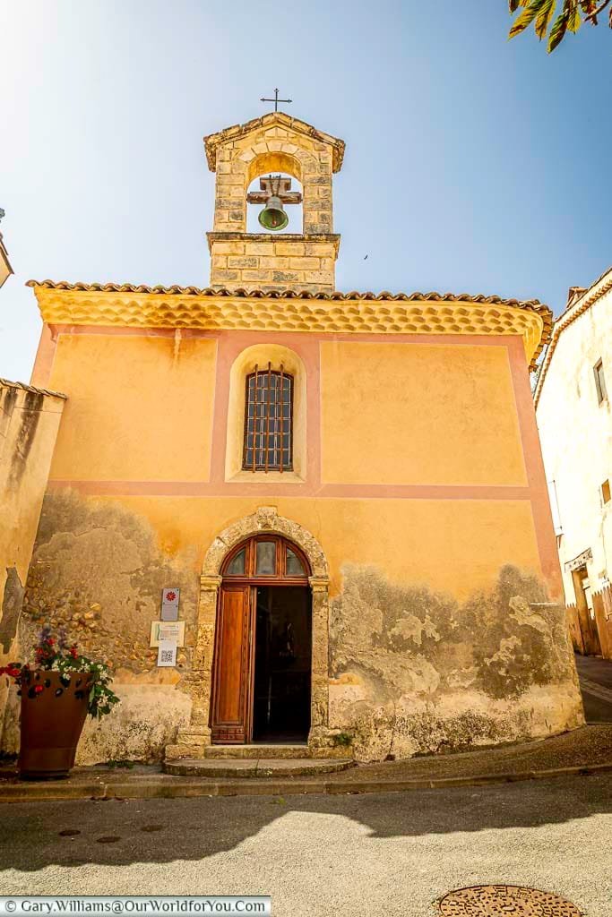 The Chapelle Saint-Mayeul in Provence stands out with its pastel-hued façade, rustic charm, and distinctive bell tower set against a clear blue sky. This historic chapel is a hidden gem in one of France’s most picturesque villages, offering cultural depth and timeless Provençal beauty.