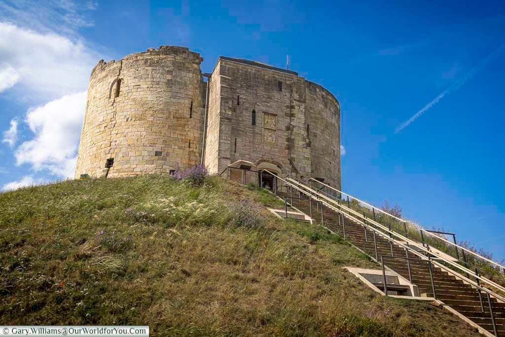 Clifford’s Tower, the dramatic stone keep of York Castle, standing proudly on a grassy mound. This landmark offers panoramic views of York and is a highlight for history lovers.
